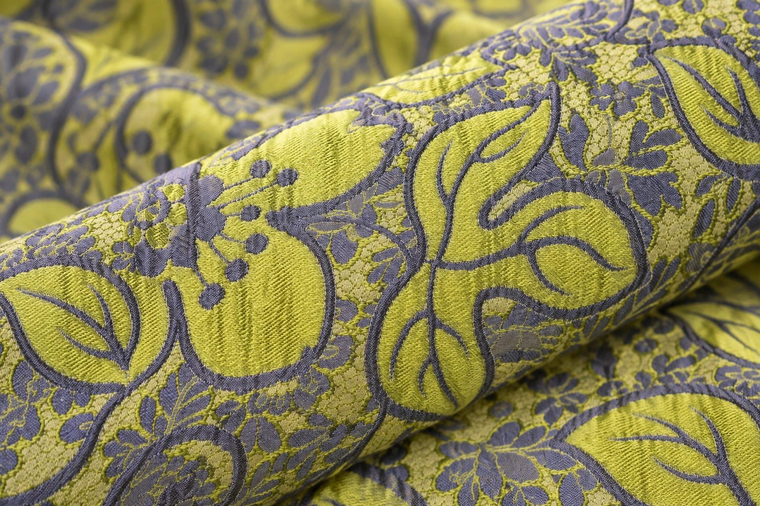 Detalle de un jacquard floral en verde lima y lila, enrollado